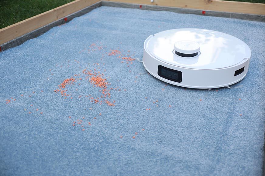 Ecovacs Deebot T10 reinigt Linsen auf einem Teppich im Saugtest.